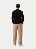 back view of a man wearing a black sweater and beige pants on a white background #color_black