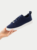 Navy blue sneaker with white sole held by a hand on a light gray background  #color_navy