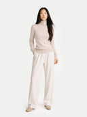 front view of a woman wearing a beige turtleneck sweater and wide-leg pants on a white background #color_warm-grey
