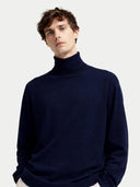 Man wearing a navy turtleneck sweater on a light gray background
