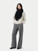 Person wearing a black scarf, white sweater, gray pants, and black shoes on a white background #color_black