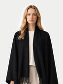 Woman wearing a black shawl with fringes on a white background.