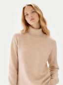 Woman wearing a beige turtleneck sweater against a light background #color_beige