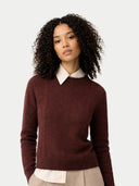 Woman wearing a maroon sweater over a white shirt on a plain background #color_deep-mahogany
