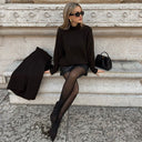 Woman in black cashmere high neck sweater sitting on stone steps — @GobiCashmere