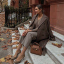 Woman in taupe cashmere double-breasted long coat on brownstone steps — @GobiCashmere