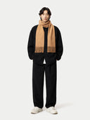 Person wearing a black outfit with a beige scarf on a white background #color_sheepskin