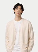Person wearing a beige cardigan over a white shirt on a light gray background #color_off-white