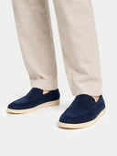 Navy loafers worn with beige pants on a white background #color_navy