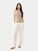 front view of Woman wearing a beige sleeveless top and white pants on a white background #color_warm-grey