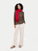 Woman wearing a red scarf, brown plaid sweater, white pants, and beige shoes on a white background #color_barberry
