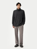 Person wearing a dark gray sweater and light gray pants on a white background #color_charcoal