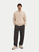 front view of a Man wearing a beige zip-up sweater and dark pants on a white background #color_beige