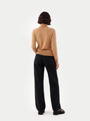 back view of a woman wearing an almond color turtleneck sweater and black pants. #color_sheepskin
