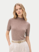 Woman wearing a brown turtleneck sweater and light-colored pants on a white background #color_timber-wolf