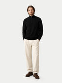 Man wearing a black sweater, beige pants, and brown shoes on a white background  #color_black
