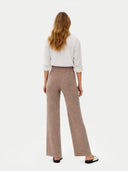 back view of a woman wearing a white blouse and brown ribbed pants on a white background #color_taupe