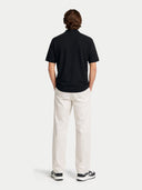back view of a black polo shirt and white pants on a white background