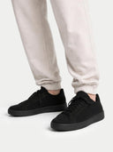 Black sneakers worn with light gray sweatpants on a white background #color_black