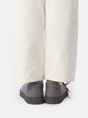 back view of a person wearing gray sneakers with a white background