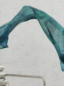 Teal fabric draped over a metal roller on a light gray background. mobile