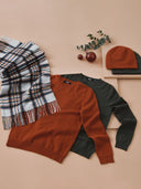 Fall-themed clothing items including a sweater, scarf, and beanie on a beige background. mobile