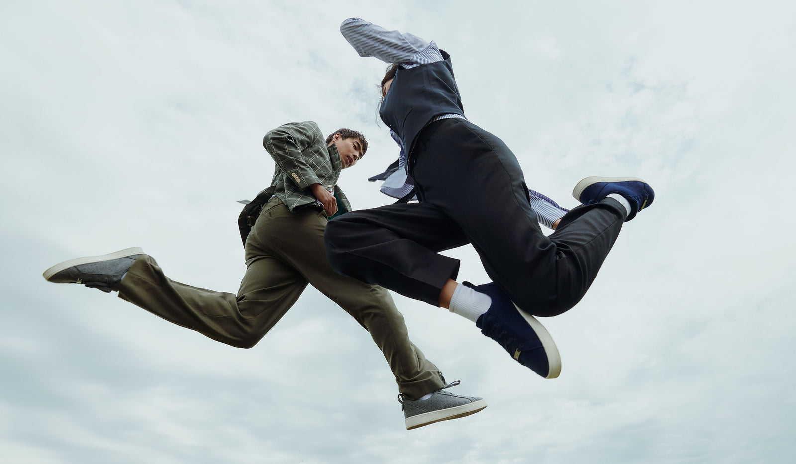 Two people in formal attire mid-air against a cloudy sky. desktop