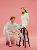 Two people sitting on a chair and a stool against a pink background. mobile