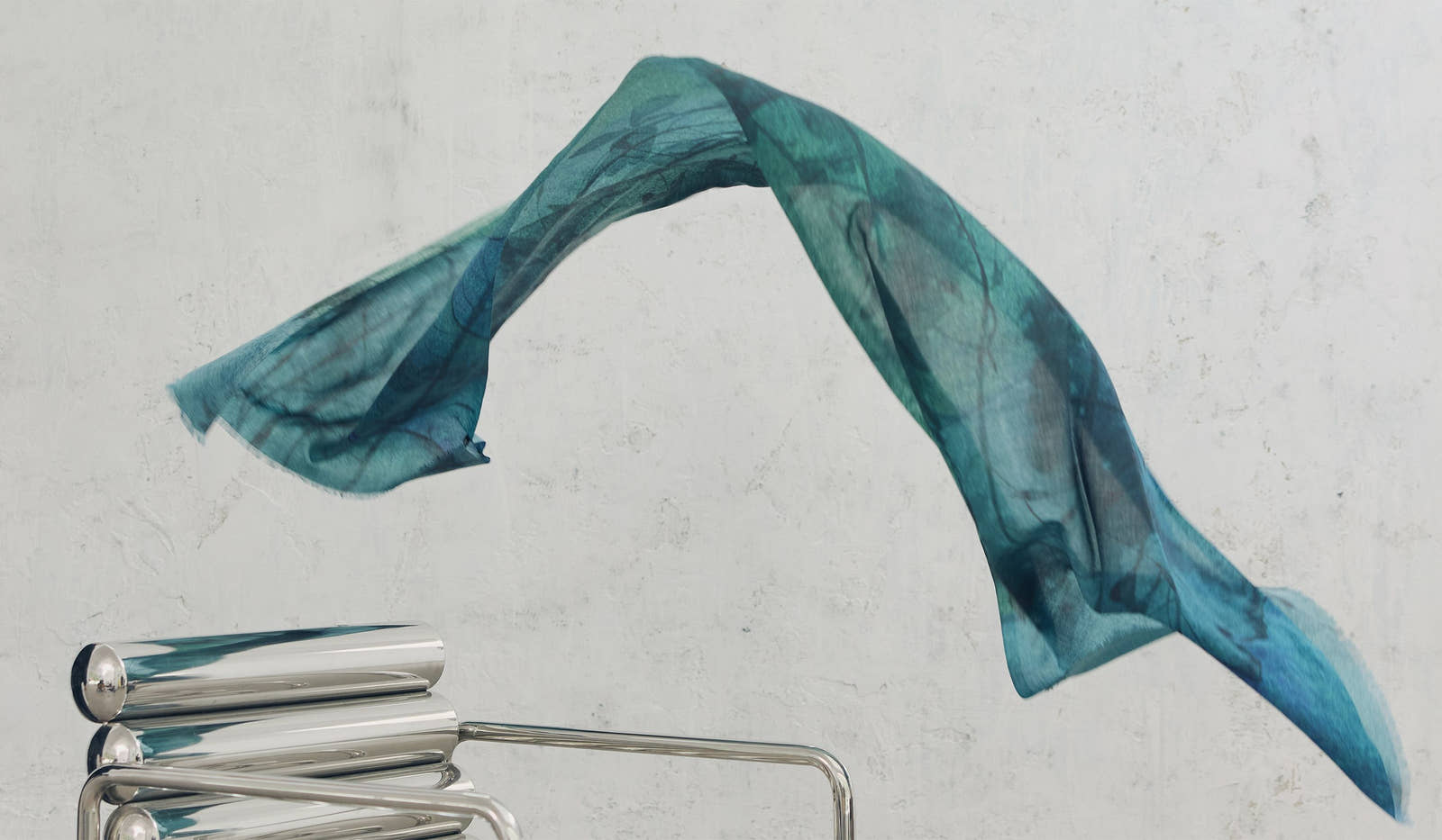 Blue scarf draped over a metal chair on a light gray background.  desktop