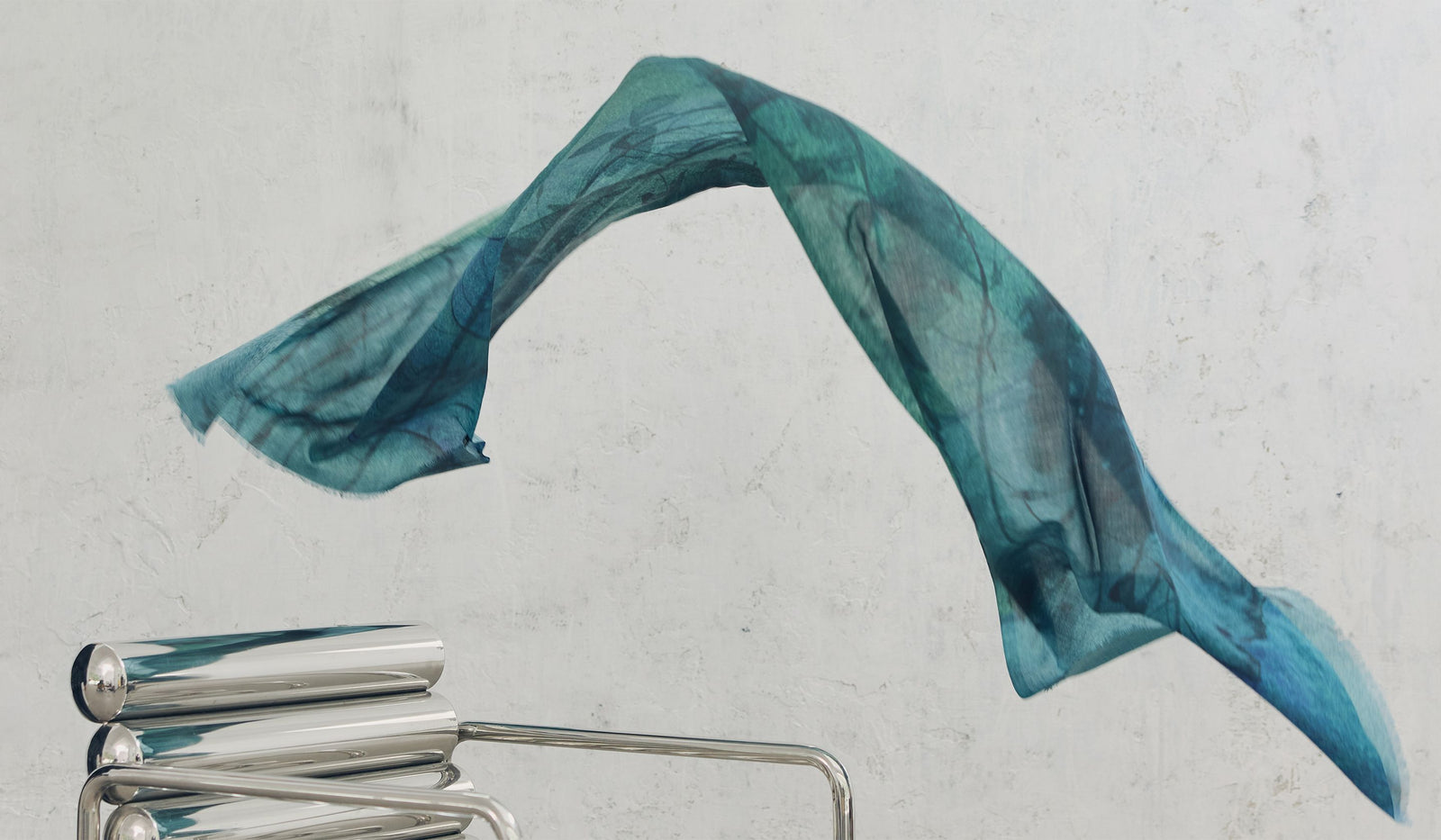 Blue scarf draped over a metal chair on a light gray background.  desktop