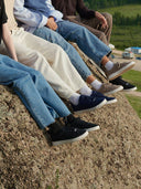 People sitting on a rock wearing jeans and shoes with a scenic background. mobile