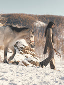 Person walking with a horse in a snowy landscape. mobile