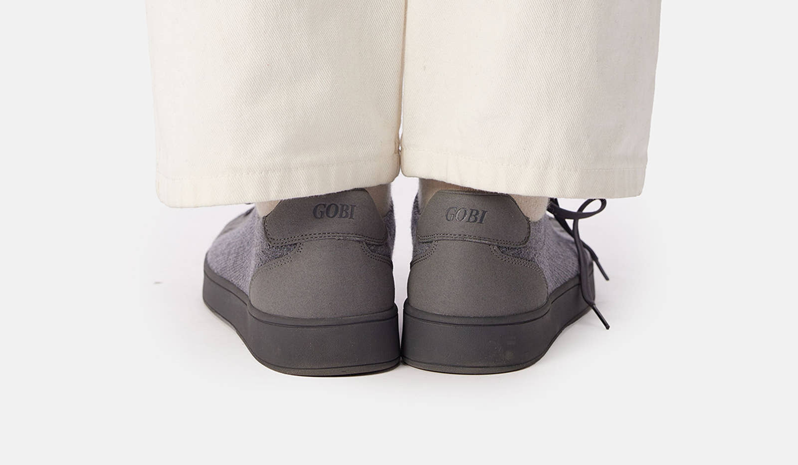 Gray shoes worn with beige pants on a white background