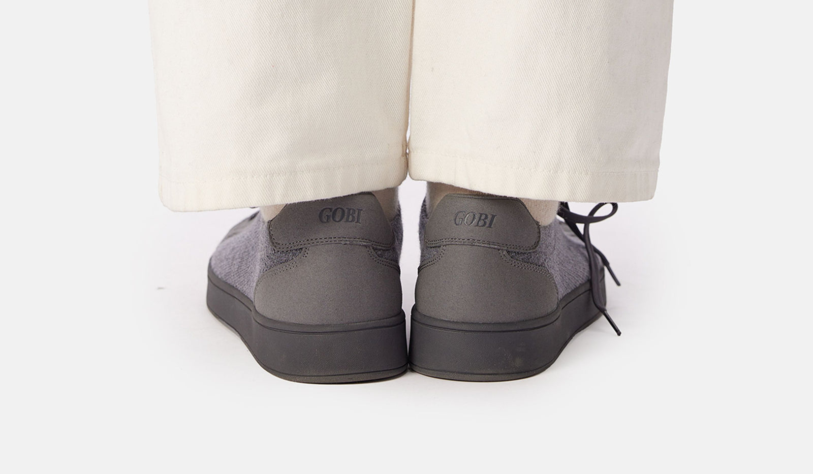 Gray shoes worn with beige pants on a white background