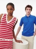 Two people, one in a red and white striped dress and the other in a blue polo shirt, standing against a plain background. mobile