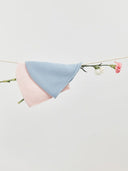 Two-toned pink and blue fabric draped over a branch with flowers on a light gray background. mobile