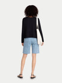 back view of a person wearing a black top and light blue shorts with a white bag on a white background #color_black