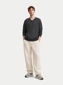 front view of a man wearing a dark gray V-neck sweater and beige pants on a white background #color_charcoal