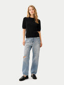 Woman wearing a black top and light blue jeans on a white background #color_black