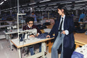 A GOBI sewing floor in Ulaanbaatar — a seamstress at her machine with a designer in a navy coat beside her