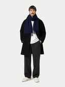 Man wearing a black coat, white shirt, dark pants, and navy scarf on a white background #color_navy
