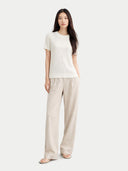 Woman wearing a white top and beige pants on a white background #color_whisper-white