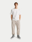 Man wearing a white t-shirt and beige pants on a white background  #color_stone-gray