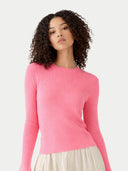 Woman wearing a pink sweater on a light gray background #color_shell-pink