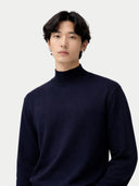 Person wearing a dark blue turtleneck sweater against a light gray background #color_navy-blazer