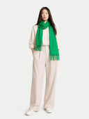 Person wearing a green scarf and beige outfit on a white background  #color_island-green