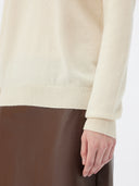 close up of a white turtle neck sweater and brown leather skirt #color_off-white
