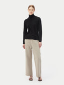 front view of woman wearing a black turtle neck sweater and gray pants on a light gray background #color_black