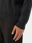 close up of a dark gray sweater sleeve and pants worn by a man on a white background #color_charcoal