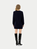 Back view of person wearing a black dress and black knee-high boots on a white background #color_navy-blazer